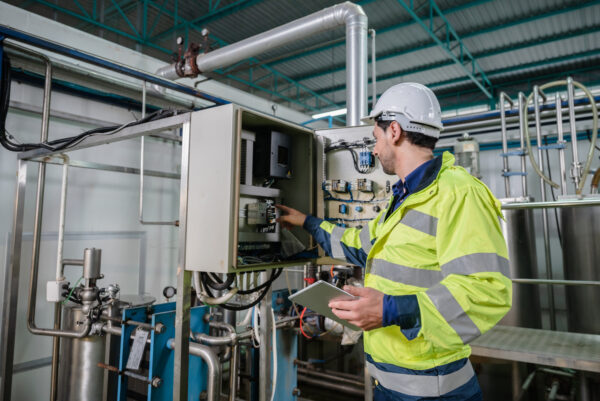 A field service engineer in a white hard hat inspects a power system.